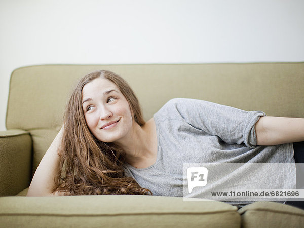 Happy young woman reclining on sofa