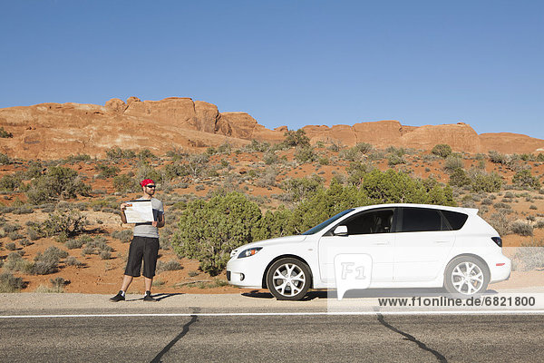 USA  Utah  Moab  Man standing beside car reading map