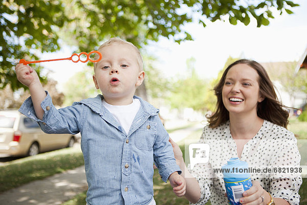 Toddler boy (2-3) and mother blowing bubbles