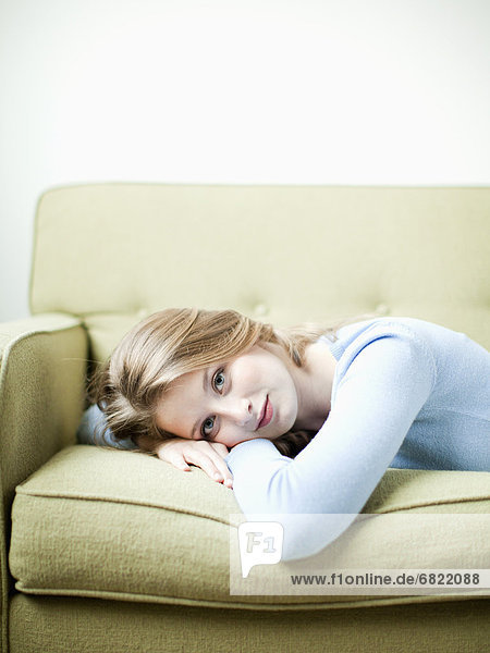Portrait of young woman lying on sofa