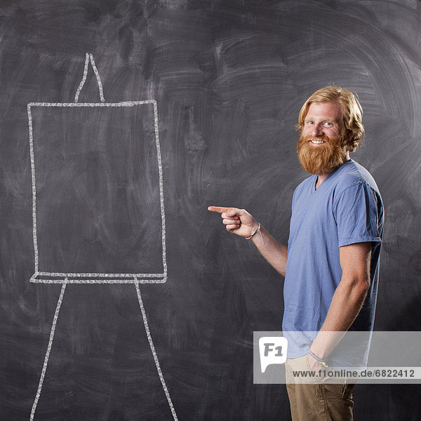 Man in front of blackboard pointing