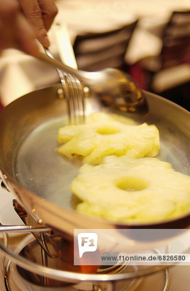 Chef cooking pineapple rings on pan  close up