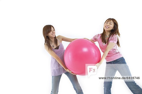 Two young women playing with a large balloon