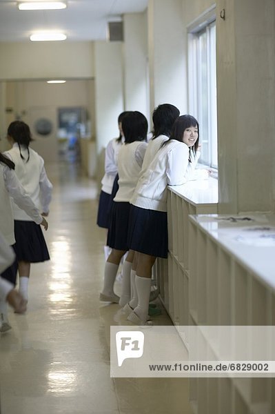 Girls looking through window in school corridor