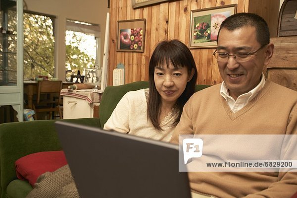 Couple using laptop in their living room