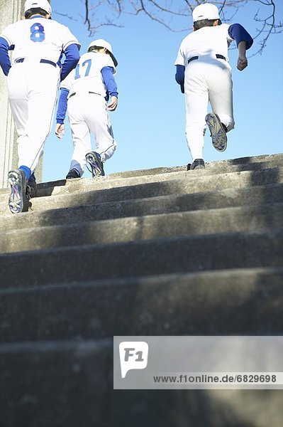Boys in baseball team running up stairs