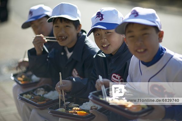 Portrait of boys in baseball uniform having lunch  sitting on bench