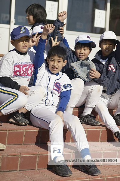 Portrait of boys in baseball uniform sitting on stairs  smiling