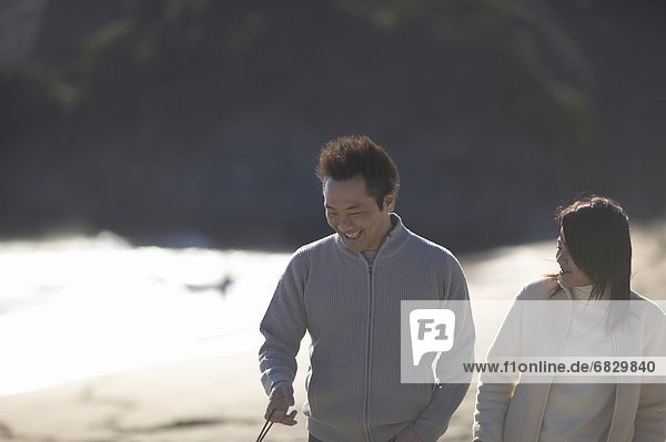 Paar Wandern am Strand  lächelnd