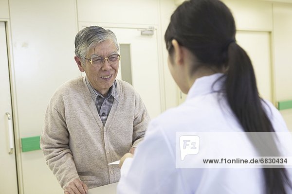 Senior man receiving medicine from female nurse
