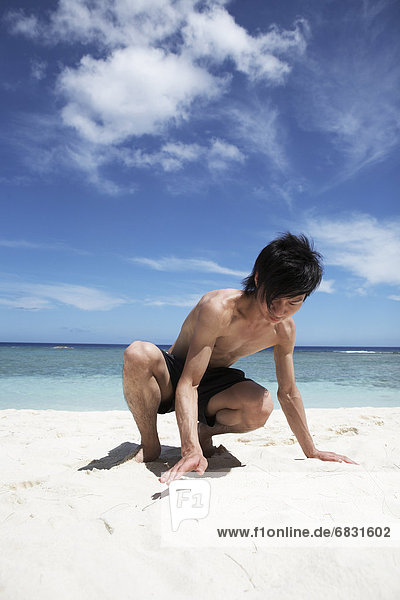 Young man playing with sand on beach  Guam  USA