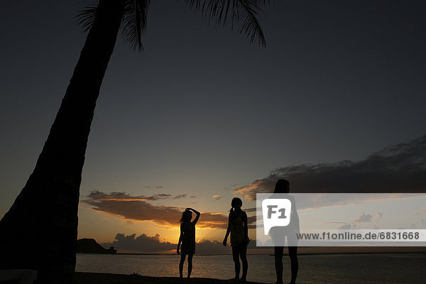 Young women standing on beach at dusk  Guam  USA
