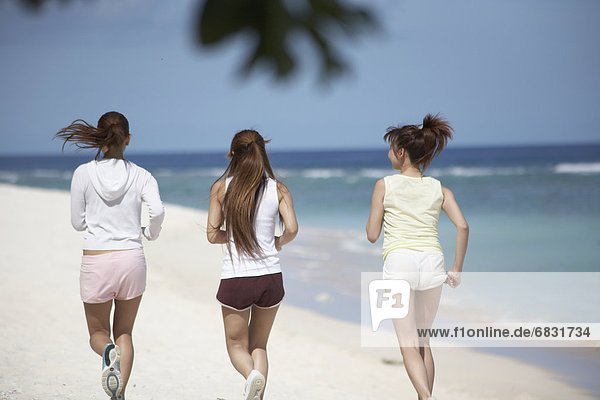 Young women jogging on beach  Guam USA