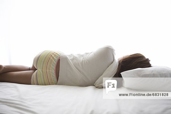 Young woman lying down on bed sleeping