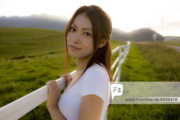 Portrait of young woman leaning on fence  looking at camera  Tochigi prefecture  Japan