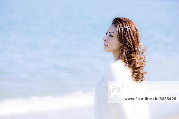 Young woman standing on beach  looking away