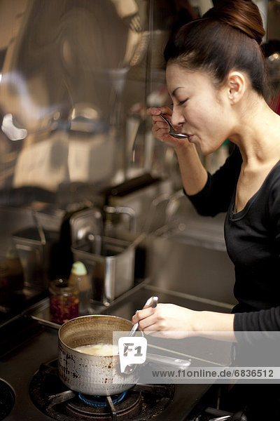 Young Woman Tasting at Kitchen in Restaurant