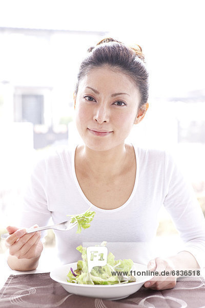 Young Woman Eating Green Salad at Table