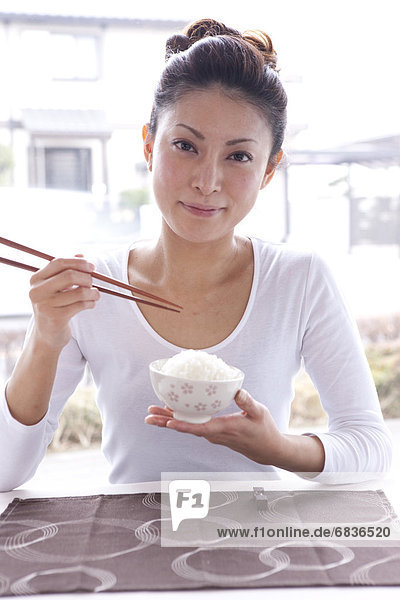 Young Woman at Table  Holding Chopsticks and Rice Bowl
