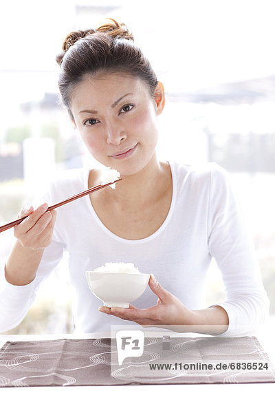 Young Woman at Table  Eating Bowl of Rice