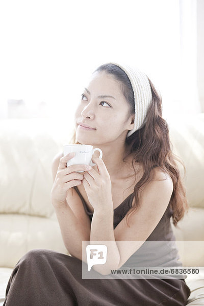 Young woman sitting on sofa  holding mug