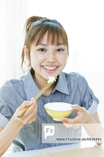 junge Frau junge Frauen Eßstäbchen Reis Reiskorn Schüssel Schüsseln Schale Schalen Schälchen essen essend isst