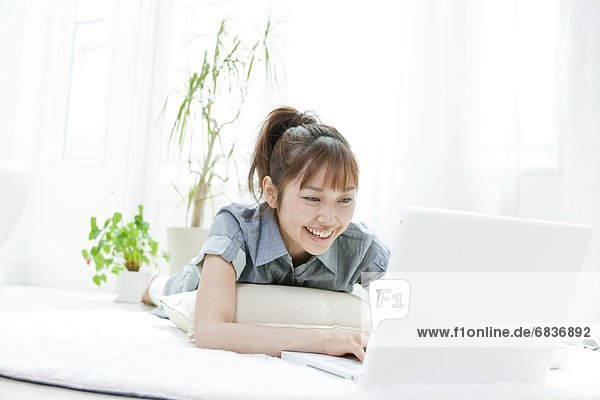 Young woman lying down and using a laptop