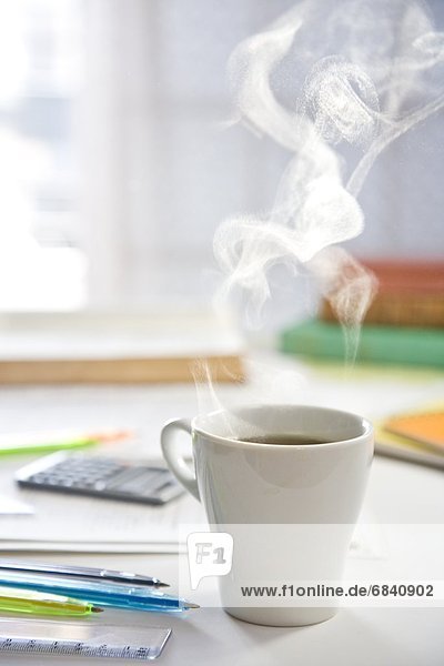 Steaming Hot Coffee Along With Study Materials on a Desk