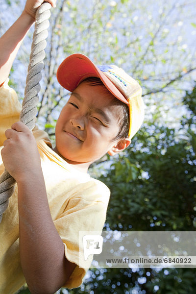 Boy hanging from a rope at a playground  Japan