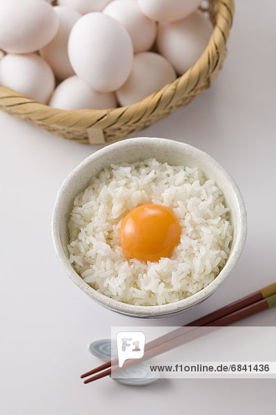 Row egg on bowl of rice  white background