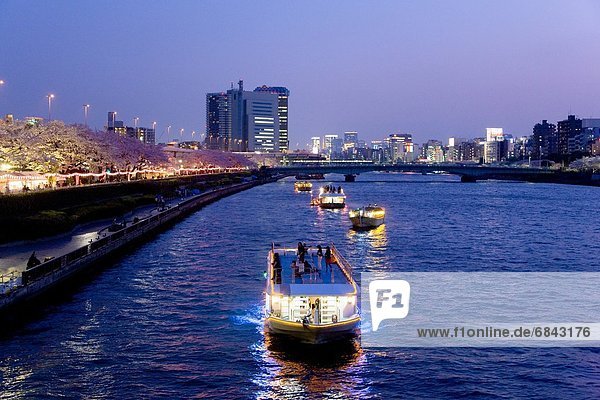 Night time view of boats on the Sumida River and the illuminated cityscape. Tokyo Prefecture  Japan