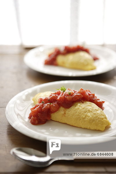 Plates of omelet with tomato sauce
