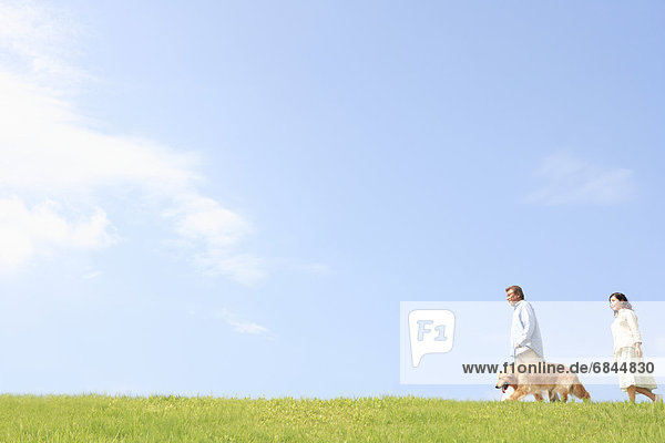 Mature Couple with Dog Walking in Field