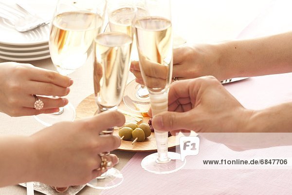 Four people holding champagne flutes and toasting at a table