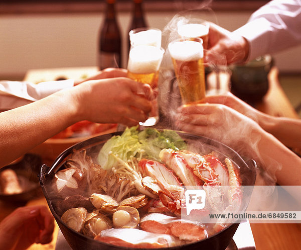 People toasting with beer over seafood dish