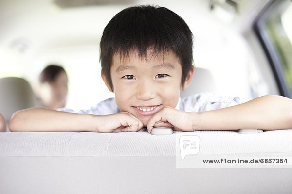 A Young Japanese Boy Sitting in a Car and Smiling