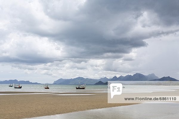 A Group of Fishing Boats Seen From the Beach With Storm Clouds Overhead. Thailand