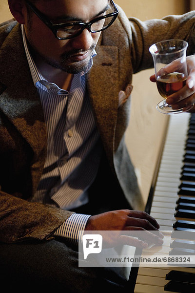 Mature Man Having a Drink and Playing Piano