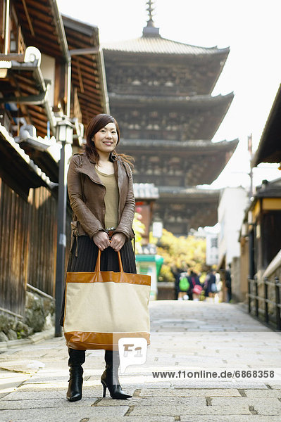 Young Woman Standing on Street With Temple in the Background