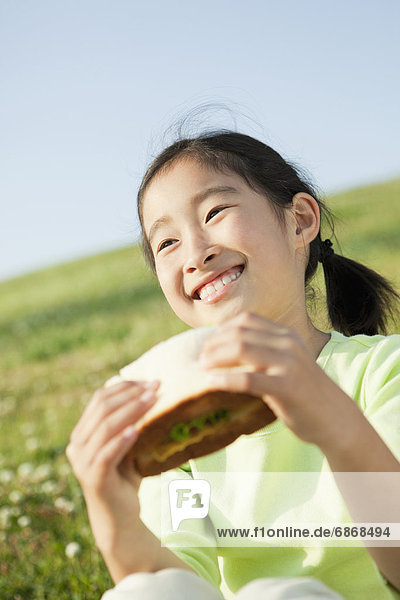 Young Girl Eating Sandwich Outdoors