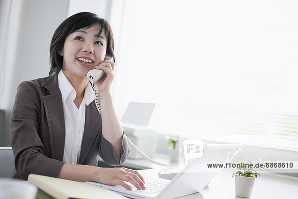 Businesswoman Talking on the Phone and Using Laptop