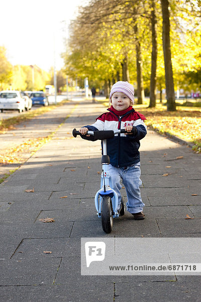 Toddler with scooter on sidewalk