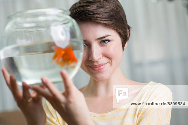 Junge Frau hält Goldfisch in einer Schale
