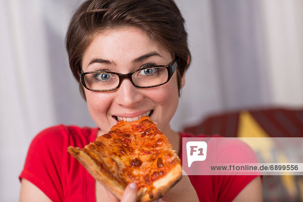 Junge Frau isst ein Stück Pizza.