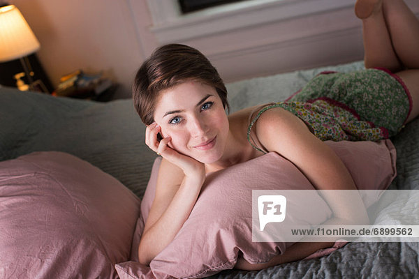 Junge Frau auf dem Bett liegend  Kissen haltend