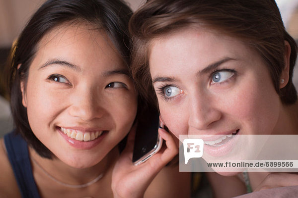 Zwei junge Frauen  die zusammen Handy hören