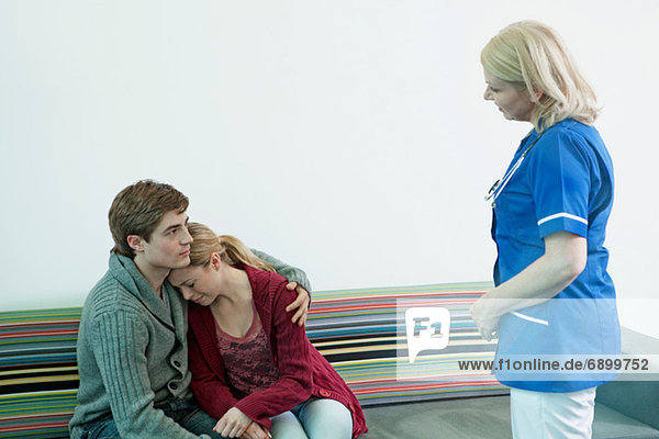 Junges Paar mit Krankenschwester im Wartezimmer des Krankenhauses