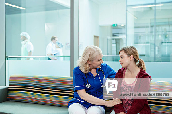 Krankenschwester im Gespräch mit Frau im Wartezimmer des Krankenhauses