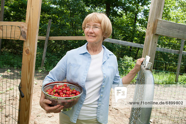 Woman holding colander with strawberries