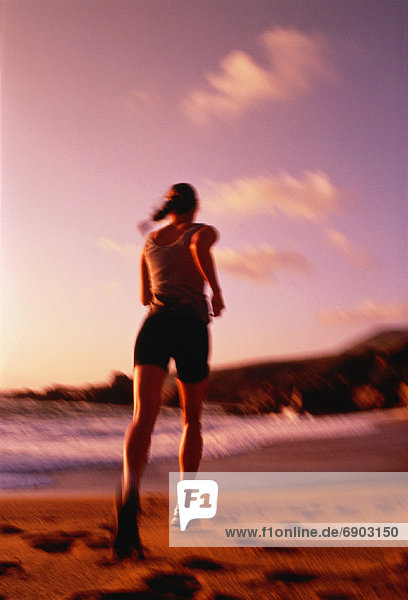 Back View of Woman Running on Beach at Sunset